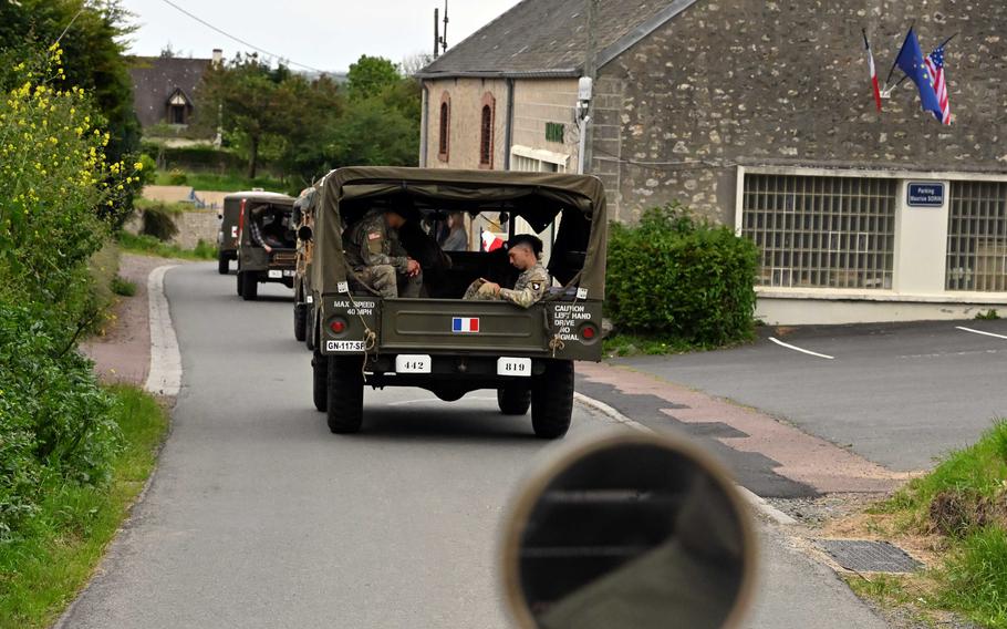 Soldiers ride in a vintage military vehicle.