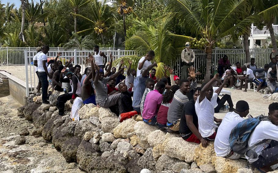 Migrants rest on the seawall after a sailboat from Haiti ran aground in Summerland Key, Fla., on March 14, 2022.