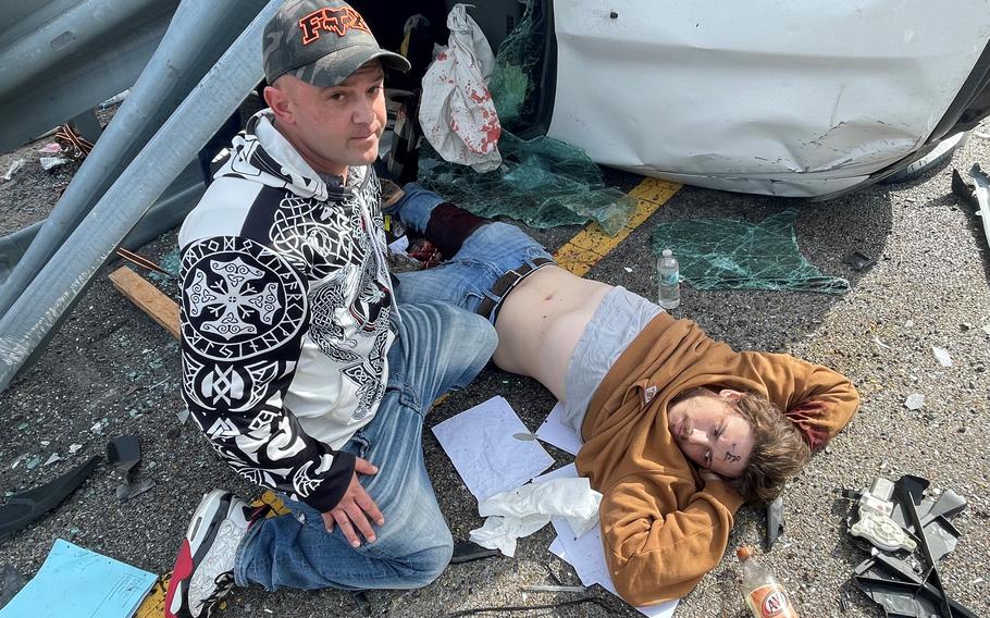 Army Sgt. 1st Class Corey Engard sits next to Colton Rogers at a crash scene in east-central Mississippi on Nov. 17, 2023. Engard applied a tourniquet to Rogers’ leg, which was severed from above the kneecap down as a result of the crash.