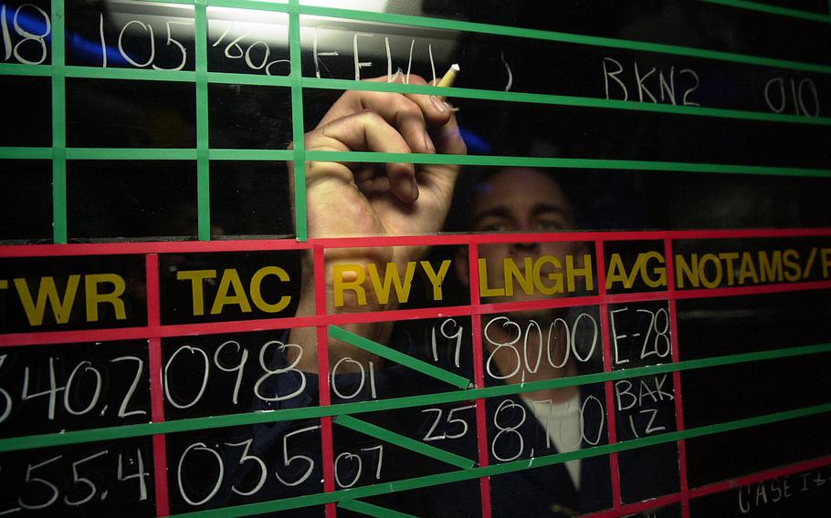 Petty Officer 2nd Class Jack Lazenby, an air traffic controller, updates flight information on a board in the USS Kitty Hawk’s air traffic control center Monday, April 15, 2002.