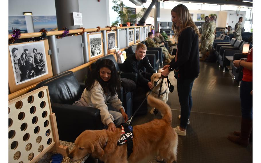 Katie Bubolz introduces her golden retrievers, Ellie, foreground, and Emma to U.S. service members at the USO center inside the passenger terminal at Ramstein Air Base, Germany, on Oct. 18, 2023. Katie and her husband, Keith, a former Army helicopter pilot, are taking the popular dogs on their first international trip to meet U.S. troops in Poland and Germany.