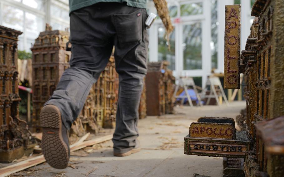 A worker walks around miniature New York landmarks during the preparations for the annual Holiday Train Show at the New York Botanical Garden in New York, Thursday, Nov. 11, 2021. The show, which opens to the public next weekend, features model trains running through and around New York landmarks, recreated in miniature with natural materials. 