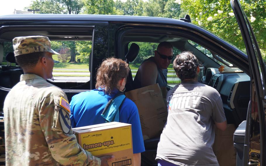 A soldier carries a box to a car