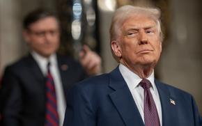 Donald Trump, wearing a dark suit, look to his right while standing on the Capitol floor.