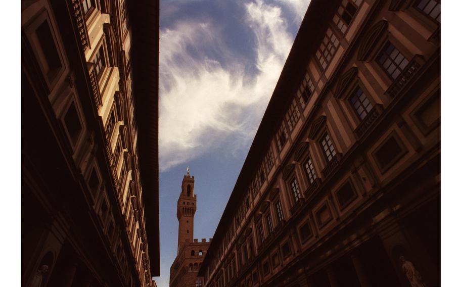 Looking up at clouds and blue sky between two buildings in Florence, Italy.