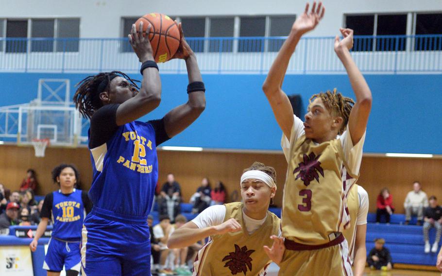 Yokota's Jai Bailey, the tournament MVP, shoots against Perry's Jahiion Francois and B.J. Hill.