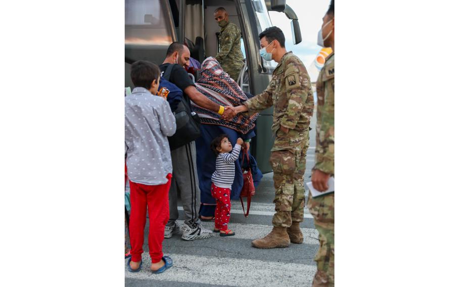 A U.S. Army Soldier shakes hands with an Afghan evacuee prior to loading a bus to Camp Bondsteel, Kosovo, Sept. 20, 2021.