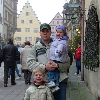 A man with two young children in a historic street.