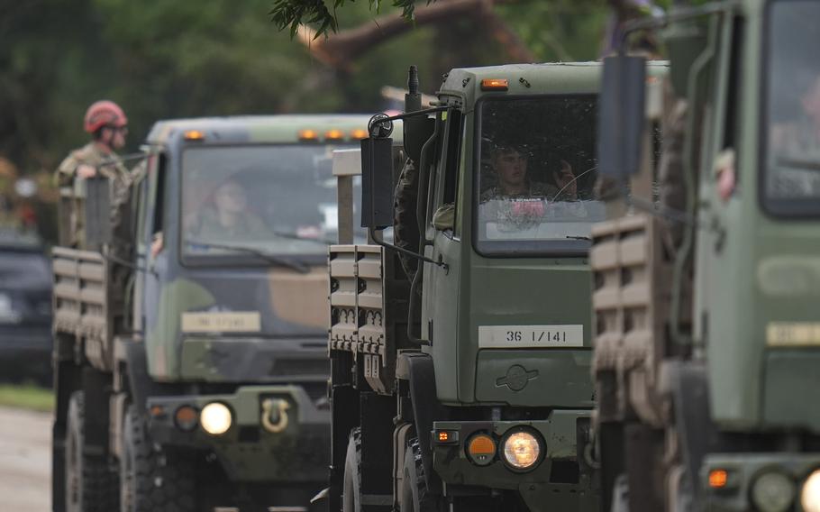 A military convoy drives on a road.