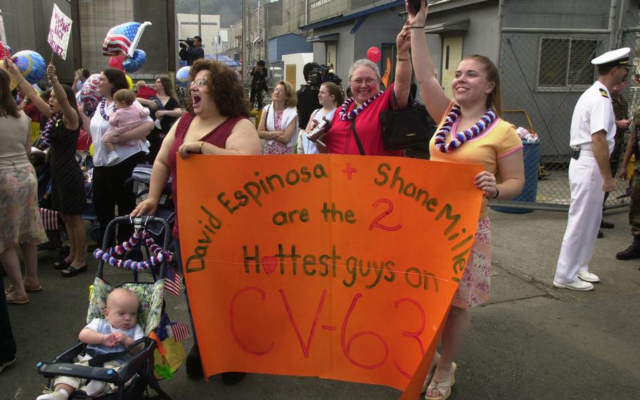 Jill Espinosa, wife of Petty Officer 2nd Class David Espinosa and Cheyene Miller, wife of Petty Officer 3rd Class Shane Miller, wave to their sailors on the USS Kitty Hawk. Both ladies were the winners in the ship’s “First Kiss Contest,” which allowed them to see their husbands earlier than most spouses — and engage in a long overdue kiss.