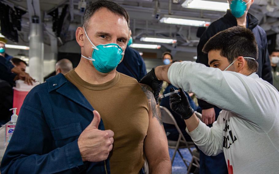 Hospital Corpsman 3rd Class Adam Santos administers the COVID-19 vaccine to Rear Adm. Scott Robertson aboard USS Dwight D. Eisenhower.