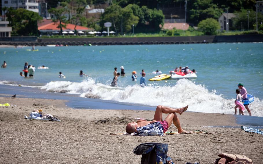 Beachgoers play and relax at Zushi Beach in Kanagawa prefecture, Japan, Tuesday, Aug. 3, 2021. 