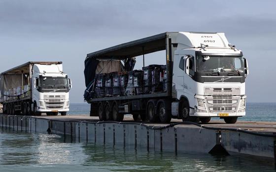 Trucks loaded with humanitarian aid cross the Trident Pier before entering the beach in Gaza on May 17, 2024.