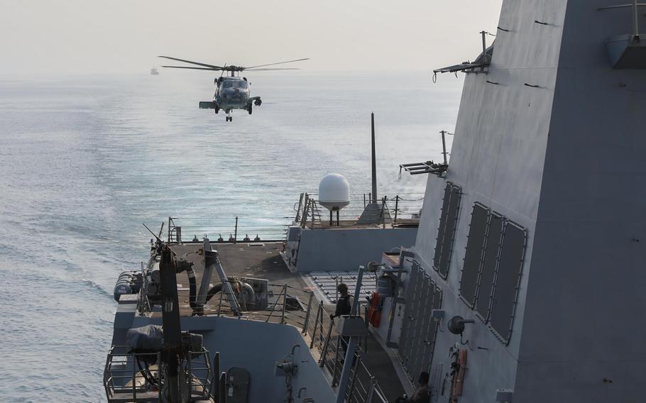 An MH-60R helicopter lands aboard the destroyer USS Thomas Hudner while transiting the Strait of Hormuz, July 28, 2023. About 100 Marines have been training in Bahrain for specialized defensive teams that could briefly travel with commercial ships through and near the waterway.