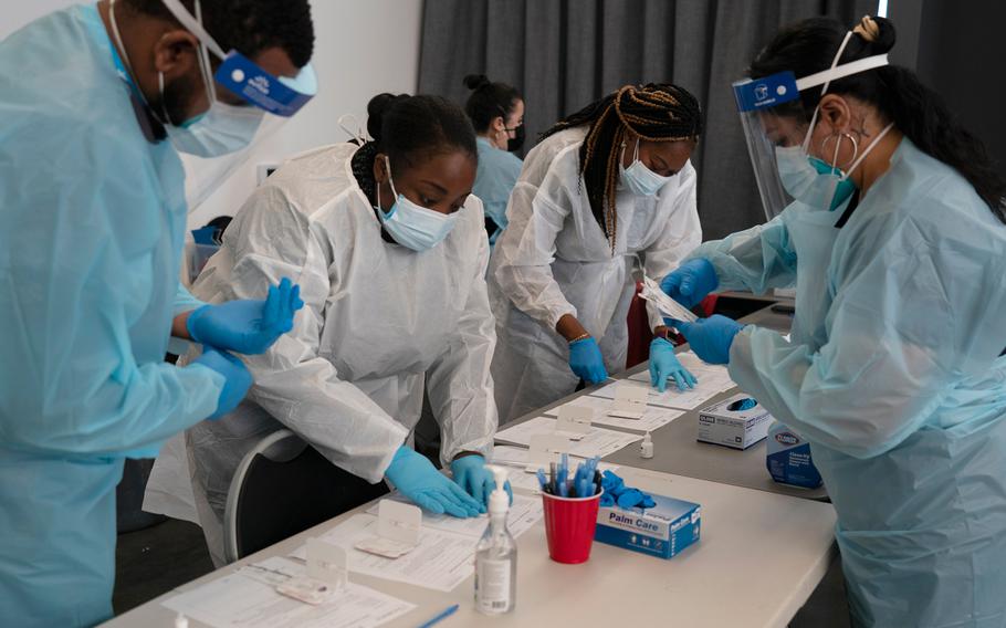 Healthcare workers Henry Paul, from left, Ray Akindele, Wilta Brutus and Leslie Powers process COVID1-9 rapid antigen tests at a testing site in Long Beach , Calif., Thursday, Jan. 6, 2022.