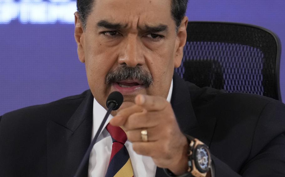 Maduro points straight at the camera while speaking at a microphone.