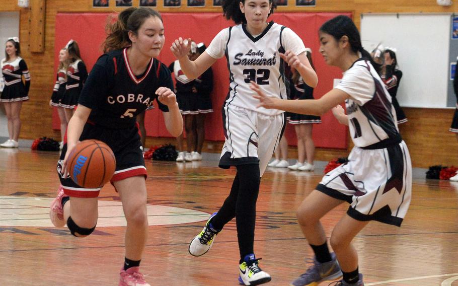 E.J. King's Aileen FitzGerald dribbles against Matthew C. Perry's Nyla Matos and Aiana Bulan during Saturday's DODEA-Japan girls basketball game. The Cobras won 51-18.