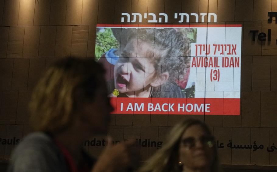 People walk past an image of 4-year-old Abigail Edan, a hostage held by Hamas, projected onto a building in Tel Aviv, Nov 26, 2023. Edan's parents were both killed by Hamas militants in the same attack in which she was kidnapped, a cross-border assault Oct. 7 that prompted Israel to declare war on Hamas. President Joe Biden has met at the White House with Abigail Edan.