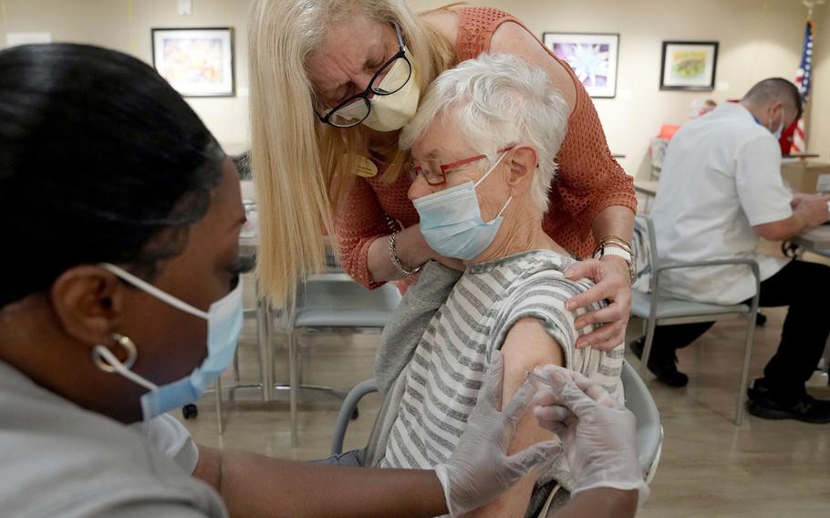 Activity program coordinator Beatriz Alcantara holds a frightened Ellen Spiegel as pharmacy tech Kimberly Singletary administers her COVID-19 booster vaccination at Belmont Village Senior Living Fort Lauderdale on Oct. 27, 2021. 