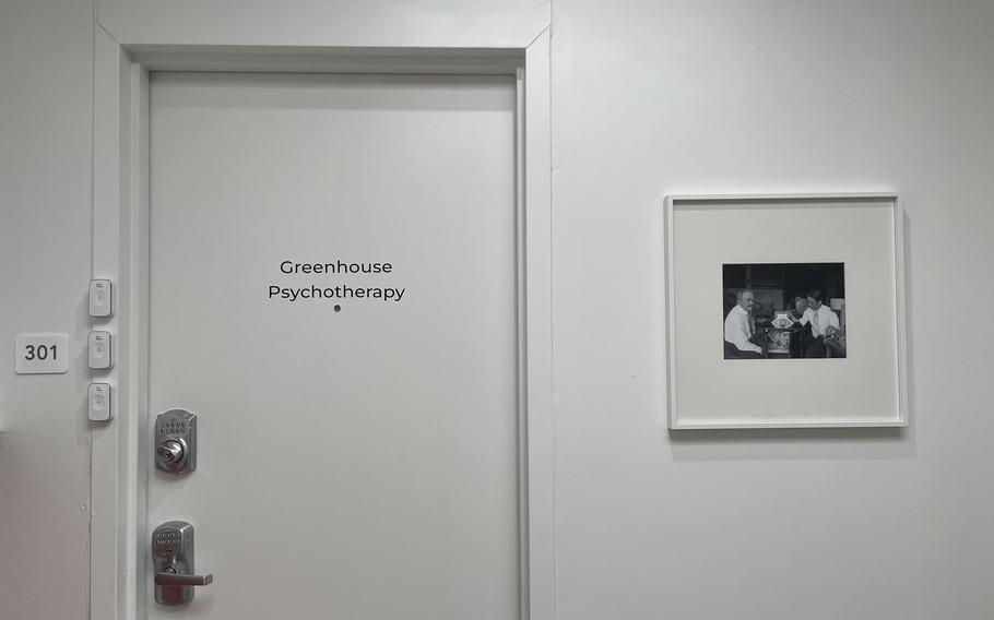 A white wall and door next to a photograph in a white frame.