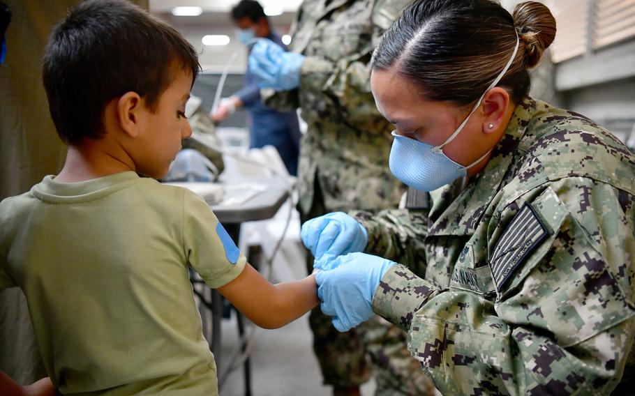 A U.S. Navy sailor assists an Afghan evacuee at Naval Air Station Sigonella, Sicily, Aug. 22, 2021. NAS Sigonella is supporting the Defense Department's mission to evacuate and relocate people from Afghanistan.