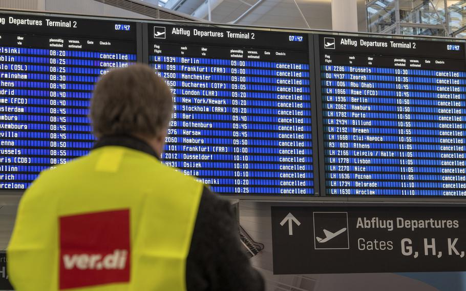 An airport employee in a strike vest of the trade union verdi stands in front of a display board at Frankfurt Airport in Germany, Friday, Feb. 17, 2023. Thousands of flights to and from German airports were canceled Friday as workers walked out to press their demands for inflation-busting pay increases. 