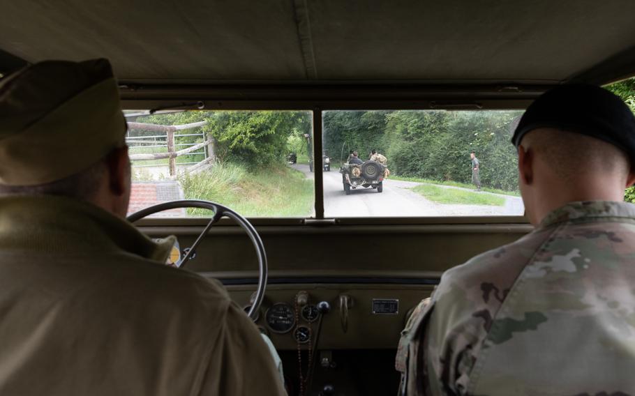 Soldiers ride in a vintage military vehicle.