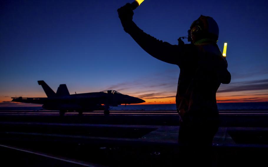 Petty Officer 3rd Class Gzavel Bolton directs the pilot of an F/A-18E Super Hornet on the flight deck of the aircraft carrier USS Harry S. Truman, Jan. 29, 2022. NATO officials aboard the Truman said Wednesday that Russian military craft had shadowed alliance ships without incident during the Neptune Strike 22 exercise.
