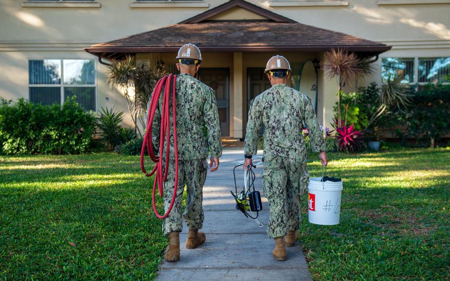 Sailors walk toward a home on Joint Base Pearl Harbor-Hickam, Hawaii, Feb. 19, 2022, to conduct a field team home visit in the wake of the November 2021 jet fuel leak at the Red Hill storage facility that caused mass drinking water contamination.