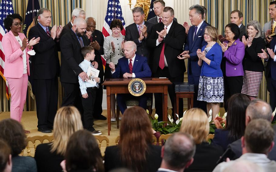 President Joe Biden hands a pen to Marine Corps veteran Kate Hendricks’ son Matthew after Biden signed a bill into law named after his late mother during an event in the State Dining Room of the White House in Washington, on Tuesday, June 7, 2022. 