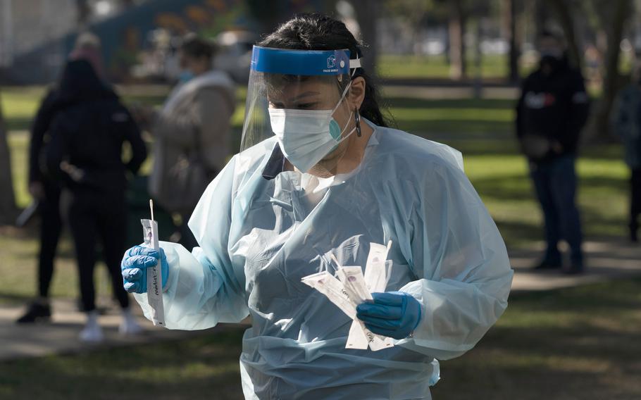 Medical assistant Leslie Powers carries swab samples collected from people to process them on-site at a COVID-19 testing site in Long Beach, Calif., Thursday, Jan. 6, 2022. 
