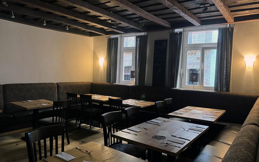 The inside of a restaurant with the ceiling supported by old wooden beams.