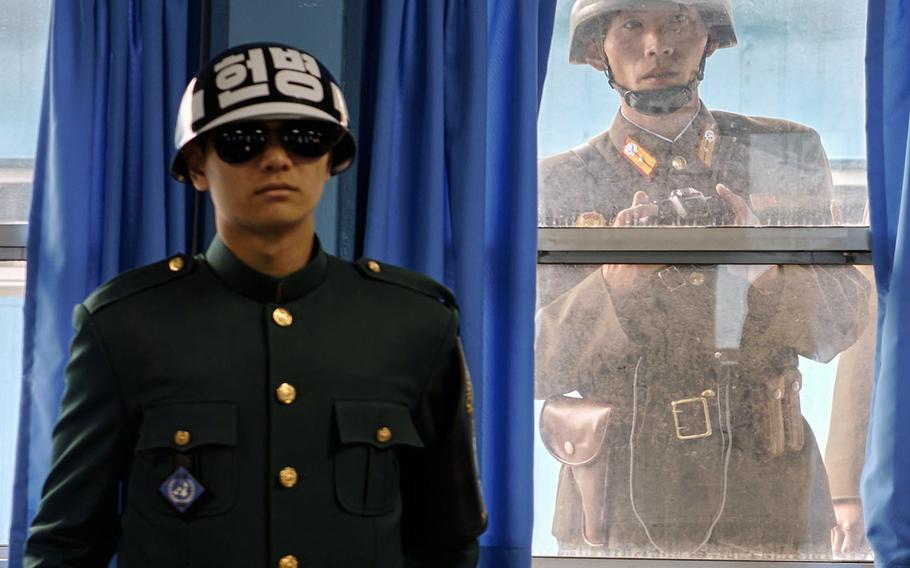 A North Korean soldier looks over the shoulder of a South Korean soldier at the Joint Security Area of the Demilitarized Zone between North and South Korea, in November 2015.