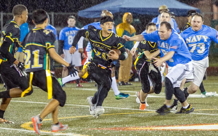 Senior Douglass Tackney, with ball, and his Robert D. Edgren teammates played flag football in the driving rain against Navy sailors at Misawa for their homecoming game.