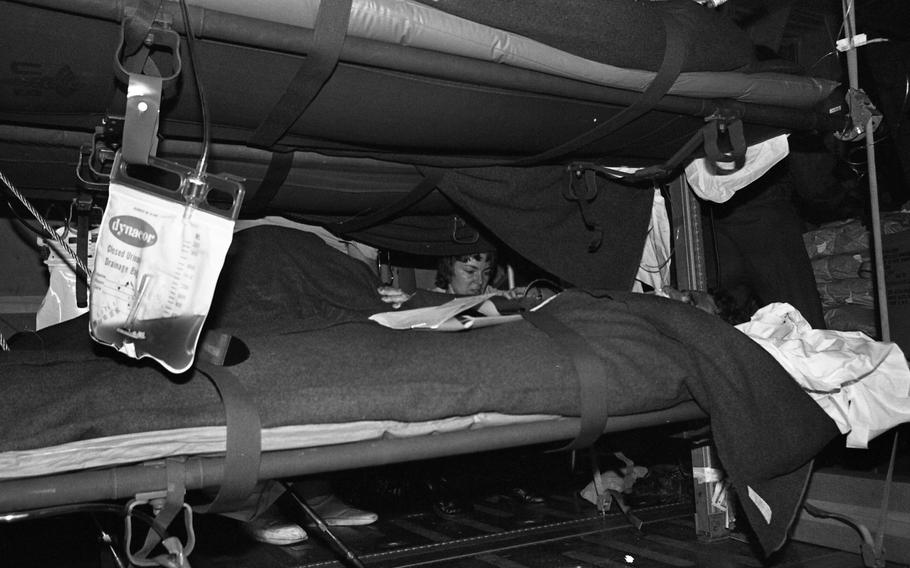 A black and white photo of a nurse hovering over a cot.
