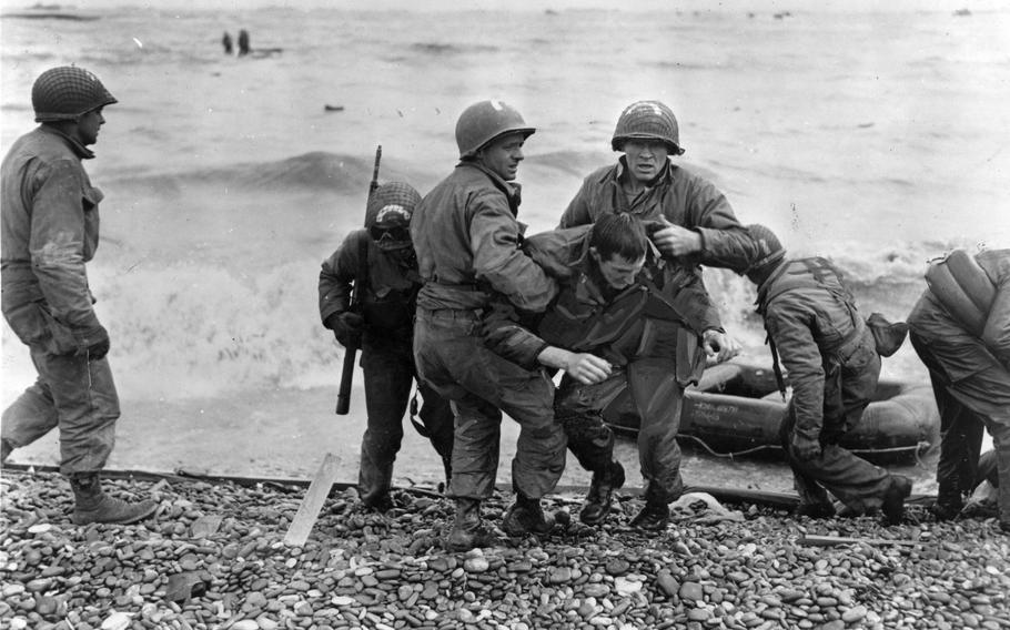 Medics from the U.S. 5th and 6th Engineer Special Brigade (ESB) help wounded soldiers on Omaha Beach. Survivors of sunken landing craft who reached the beach by using a life raft are recovered by other troops. June 6th, 1944, D-Day.