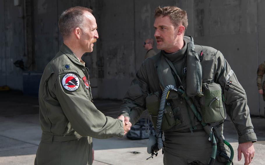 Air Force Lt. Col. Michael Mickus, commander of the 355th Expeditionary Fighter Squadron, right, greets Air Force Lt. Col. Shaun Loomis, 480th Expeditionary Fighter Squadron commander, at Kadena Air Base, Japan, March 28, 2023.