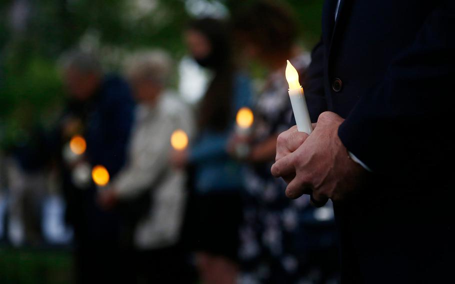 Gold Star family members hold electric candles and carnations during a solemn ceremony at the edge of the reflecting pool in the Memorial Grove at the National Veterans Memorial and Museum.