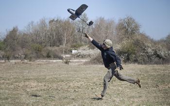 A soldier hand-launches a handmade drone in a field
