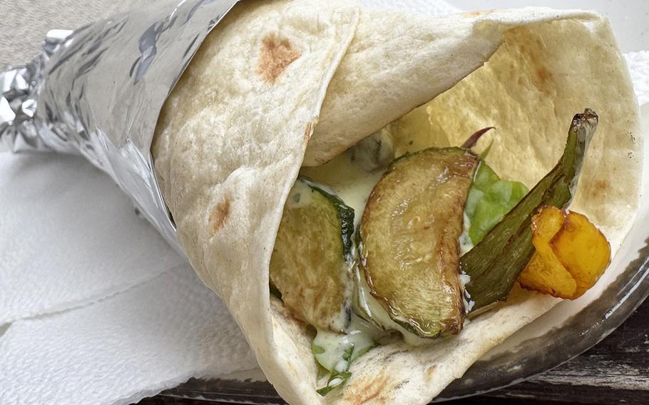 A wrap with pickles and other vegetables showing out the end