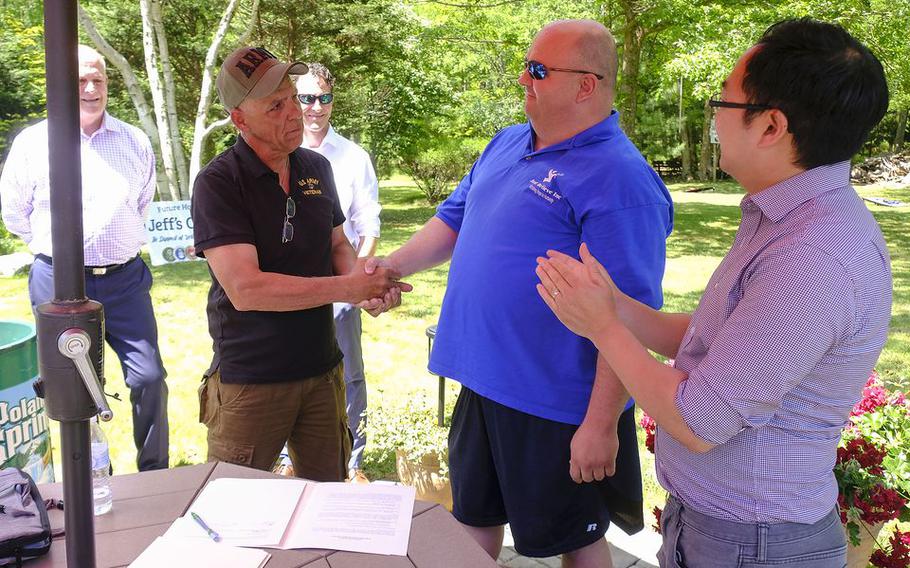 Rep. Andy Kim (D-NJ), right, applauds as Barnegat property owner Marty Weber, left, shakes the hand of Just Believe homeless outreach organization director Paul Hulse. Weber had just signed a letter of intent to donate a 36-acre site along Route 72 that will include a group home, treatment facility and retreat for homeless veterans struggling with addiction and mental illness. Dr. Joseph Savon and Joel Alvano or New Life Addiction Services look on. Thursday, May 27, 2021. Barnegat, N.J.