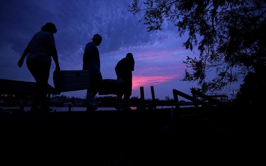 People carry supplies to their boat at dusk in the aftermath of Hurricane Ida, Wednesday, Sept. 1, 2021, in Jean Lafitte, La. 