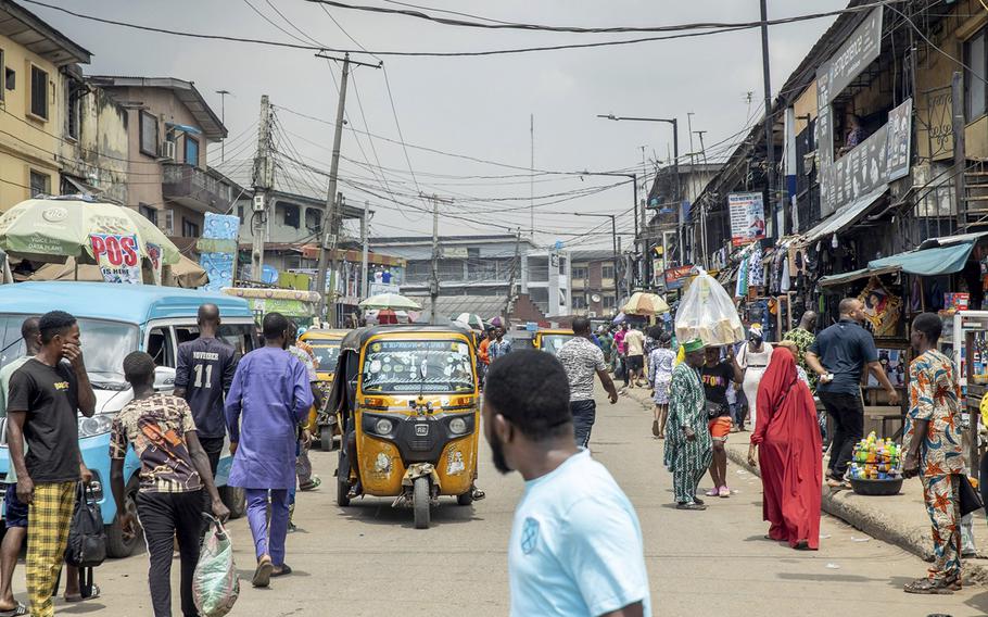 Pedestrians and auto-rickshaws make their way down a street in Lagos, Nigeria, on Sept. 24, 2022. 