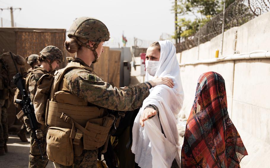 A Marine checks two civilians during processing through a checkpoint during an evacuation at Hamid Karzai International Airport, Kabul, Afghanistan, Aug. 18, 2021.