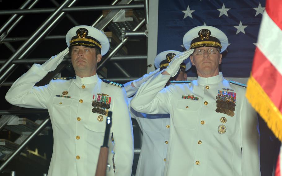Three men in white Navy uniforms salute.