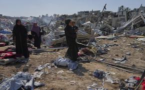 Palestinian women check the destruction after Israeli military strikes in a tent camp for displaced people near Al-Aqsa Hospital, in Deir al-Balah, Thursday, Aug. 21, 2025. (AP Photo/Jehad Alshrafi)