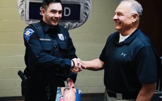 South Bend police officer Matthew Hegedus-Stewart, left, and retired South Bend police Lt. Gene Eyster during their first meeting at the South Bend Police Department in South Bend, Ind. on March 22. Hegedus-Stewart is holding a picture of himself from Dec. 22, 2000, the day he was abandoned at 2 days old. 