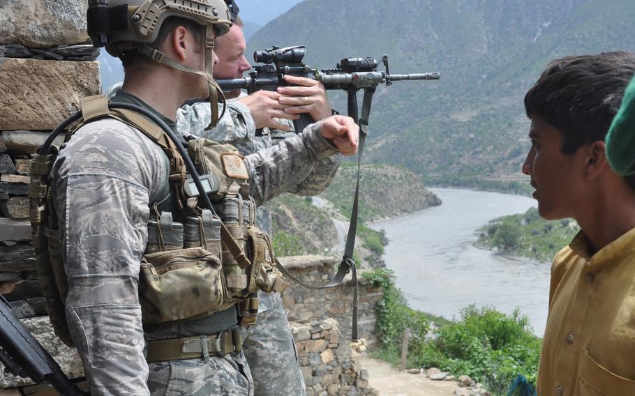 Capt. Jeffrey Hinds, then A Company commander, center, uses his rifle scope to look at a suspected insurgent stronghold across the Kunar River from the village of Spin Kay during a patrol on Aug. 2, 2010.