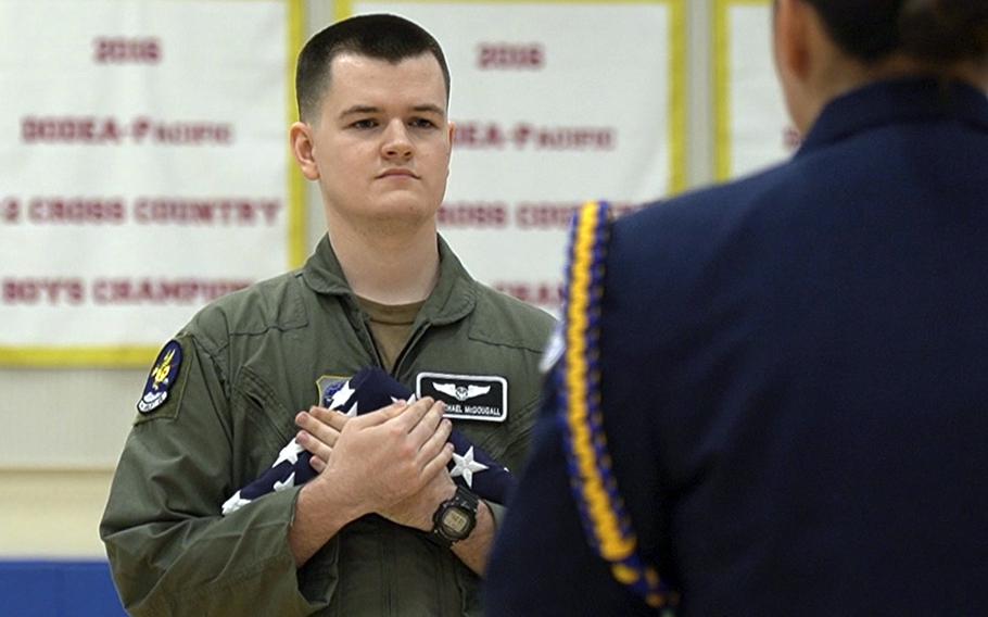 Senior Airman Michael McDougall presents a combat flag to Yokota High School during a ceremony at Yokota Air Base, Japan, Thursday, May 11, 2023. 