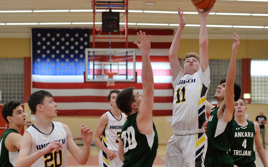 Ansbach’s Benjamin Schuck takes a shot against Ankara’s Andrew Lofay, left, and Adeeb Ahang  in a Division III game at the DODEA-Europe basketball championships in Baumholder, Germany, Feb. 16, 2023. Ansbach won 51-11